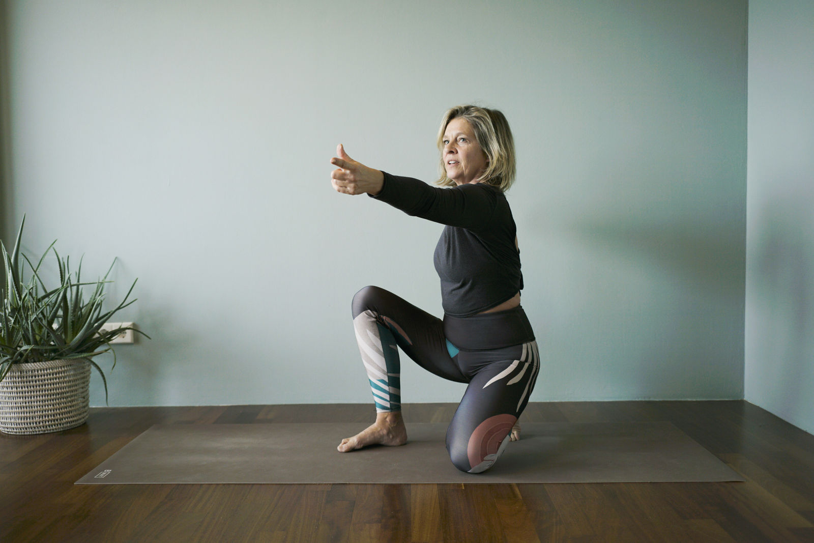 Yogalehrerin im Ausfallschritt mit nach vorne ausgestreckten Armen